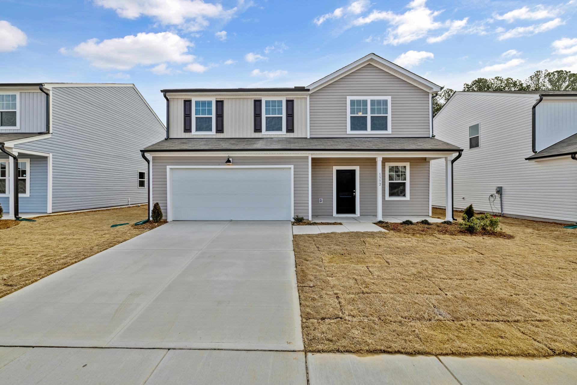 A modern suburban home with a driveway and front lawn, showcasing residential real estate.