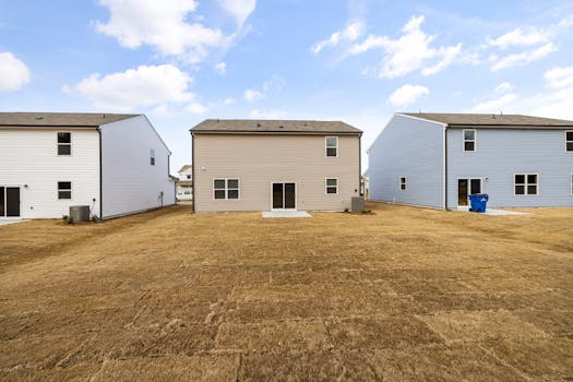 A row of modern suburban homes with freshly laid dry lawns under a bright sky.