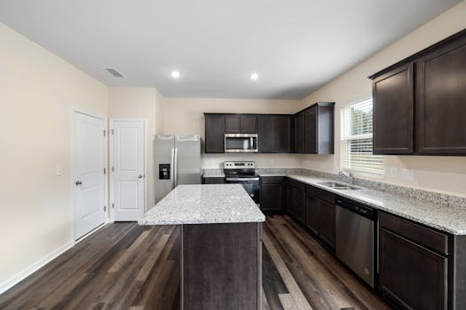 Spacious modern kitchen featuring granite countertops and dark wood cabinetry with stainless steel appliances.