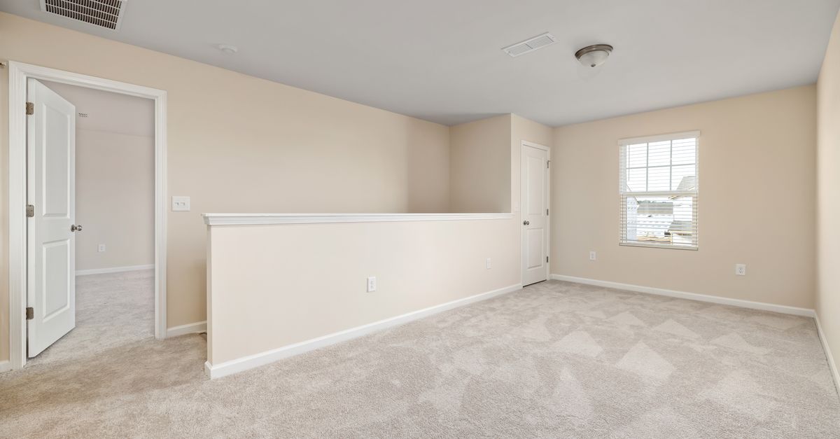 A bright, empty room with beige walls and carpet, ready for interior design ideas.
