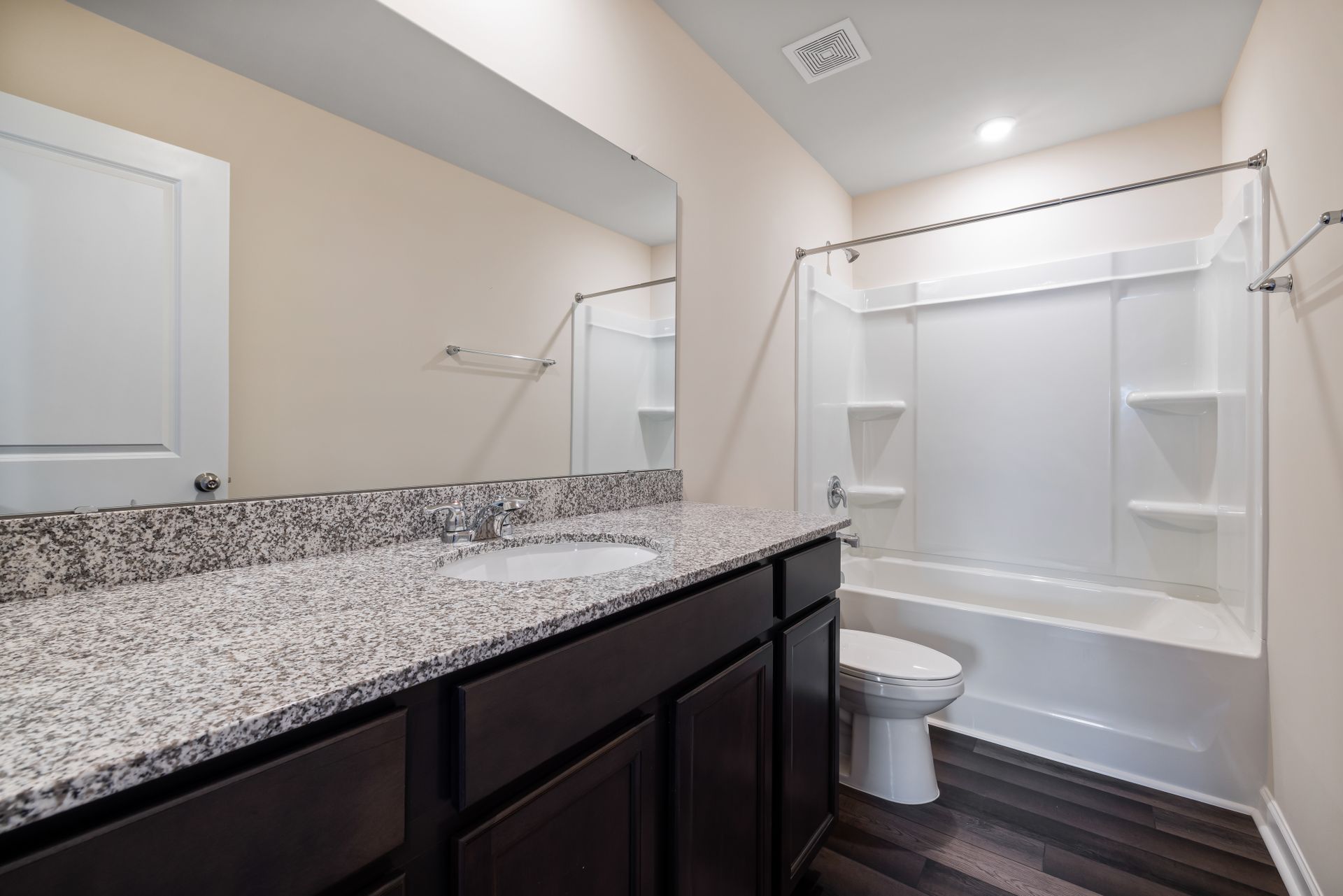 Spacious modern bathroom featuring granite countertops and a bathtub shower combination.