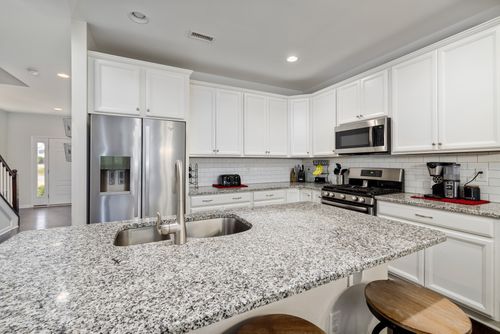 Free Spacious kitchen featuring granite countertops, white cabinets, and stainless steel appliances. Stock Photo