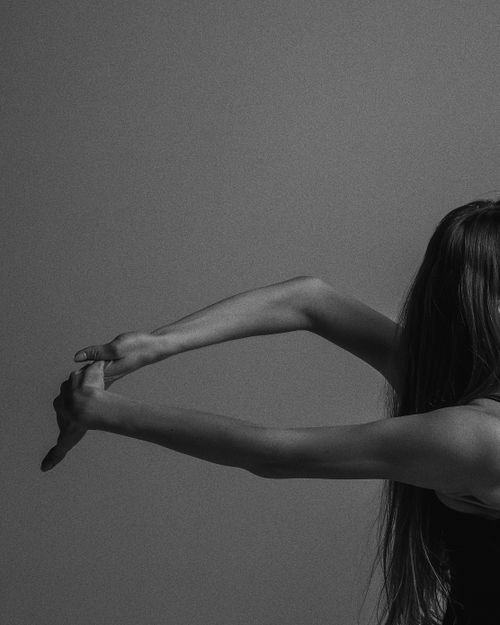 Free Black and white close-up of a woman stretching, showcasing elegance and fitness. Stock Photo