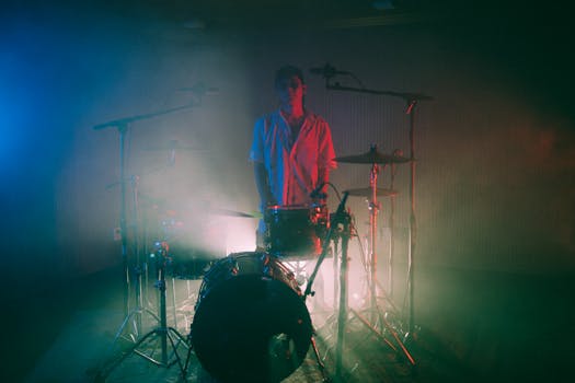 A musician playing drums in misty, colorful lighting creates a captivating scene. Perfect for music-themed content.