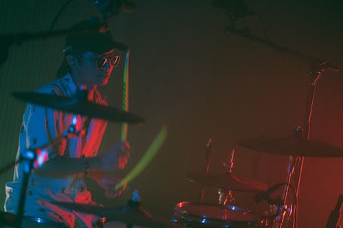 A Man Wearing Sunglasses while using Drums