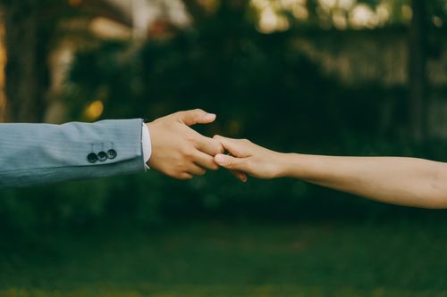 Free Close-up of a couple holding hands, symbolizing love and connection in an outdoor setting. Stock Photo