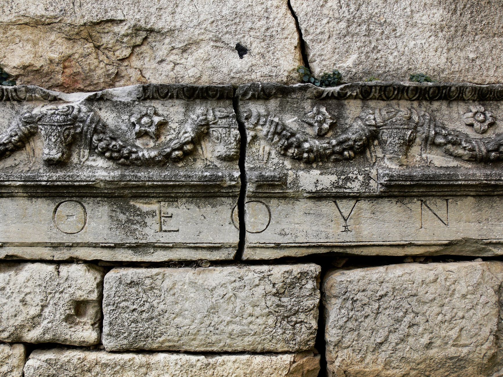 Close-up of an ancient Roman stone wall with decorative carvings and visible cracks in Bursa.