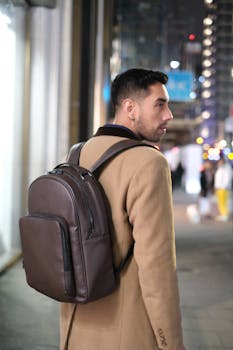 A stylish young man with a backpack explores London at night.
