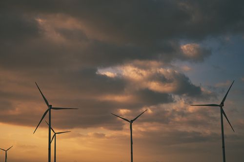 Free Silhouetted wind turbines under dramatic sunset clouds, symbolizing renewable energy. Stock Photo