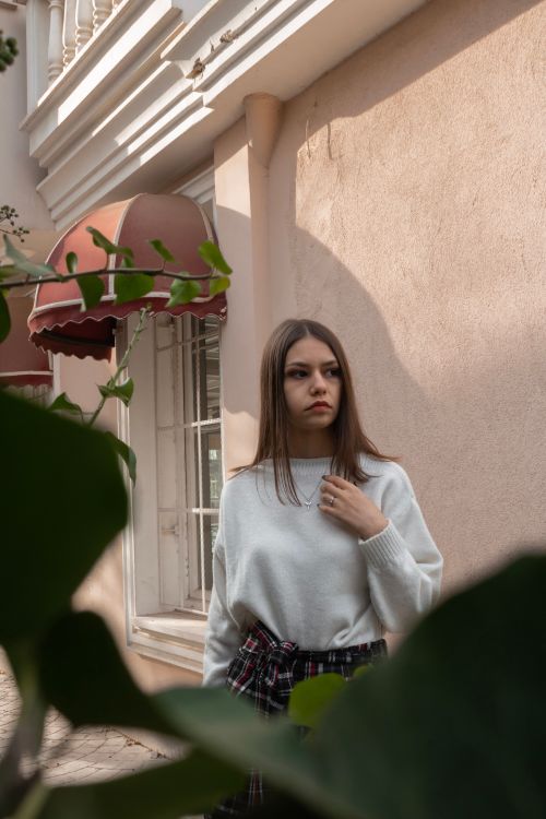 Free Stylish young woman posing on a sunny street with classic architecture backdrop. Stock Photo