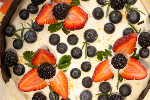 Delicious dessert topped with fresh strawberries, blackberries, blueberries, and cream.