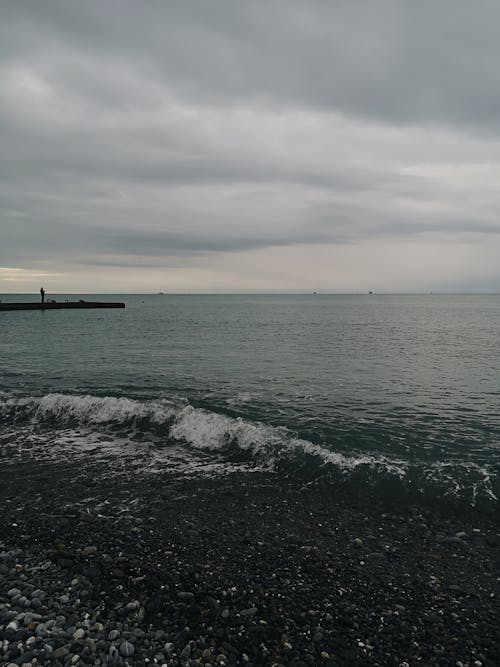 Foto profissional grátis de à beira-mar, céu sombrio, costa