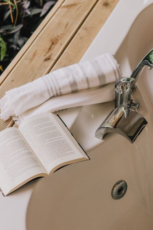 Free A serene setup of a bathtub with open book and towel, perfect for relaxation. Stock Photo