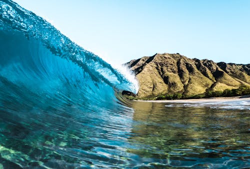 Blue Water Waves Near Mountain under Blue Sky