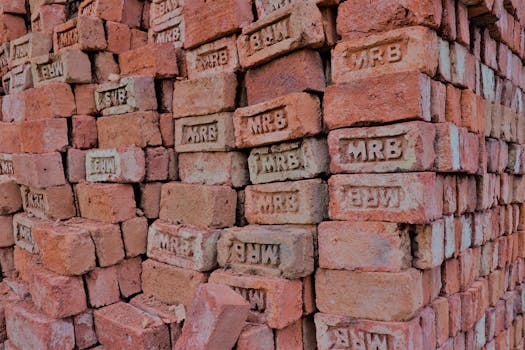 Stacks of red bricks labeled MRB at an outdoor construction site.