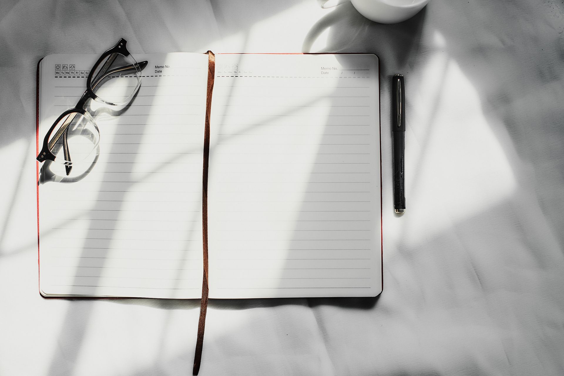 Open notebook with eyeglasses and pen on a table, ideal for productivity themes.