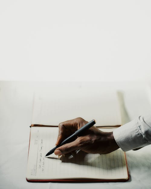 Free Person Writing on a Notebook Stock Photo