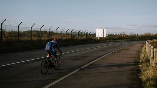 Free A cyclist rides along an empty road, showcasing a peaceful, outdoor biking scene. Stock Photo