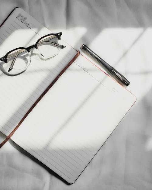 Black Framed Eyeglasses on Blank Notebook