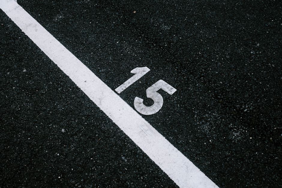 Asphalt surface with the number 15 beside a white line, ideal for transportation themes.
