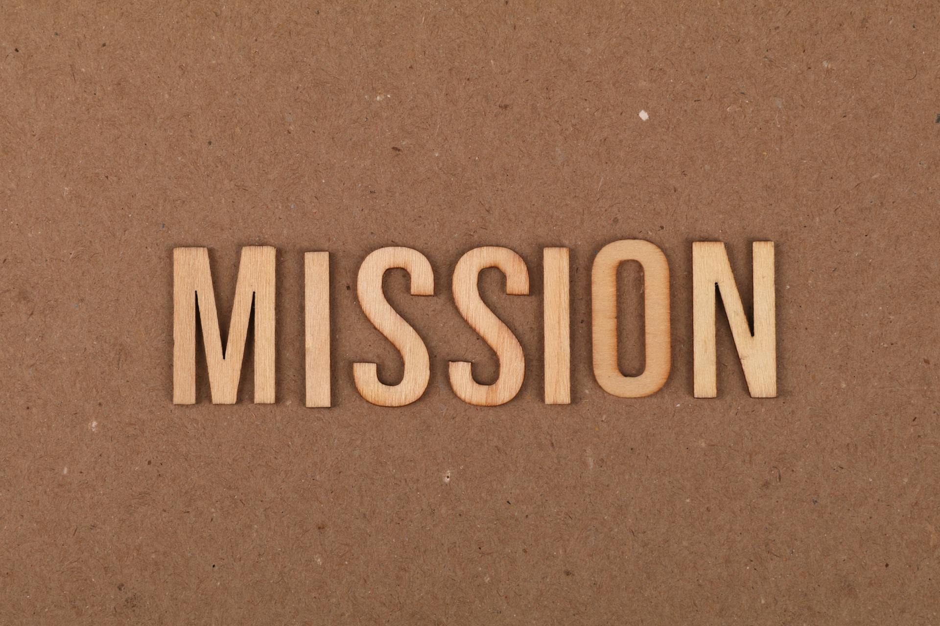 Wooden letters spelling 'MISSION' on textured cardboard background, emphasizing goals and purpose.