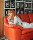 Woman in White Long Sleeve Shirt Sitting on Red Leather Couch