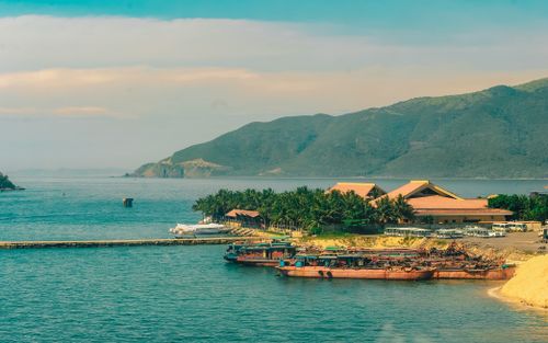 Free A tranquil coastal scene featuring boats, a resort, and lush green mountains. Stock Photo