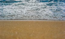 阳光明媚的海滩上，特写镜头捕捉到宁静的海浪轻抚沙质海岸线的画面