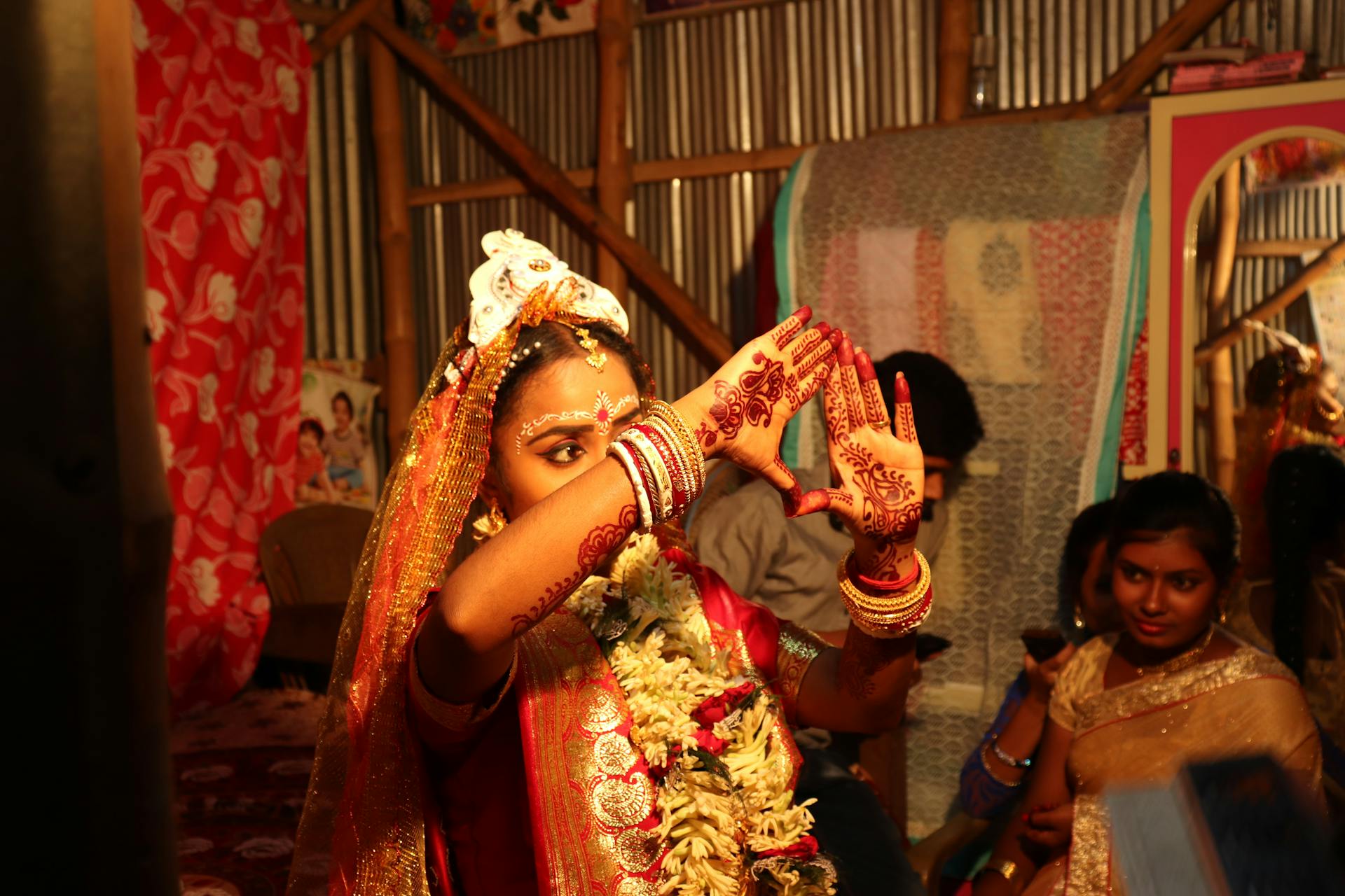Beautiful Indian bride in a vibrant sari during a Bengali wedding ceremony, showcasing intricate henna designs.