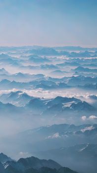 Captivating drone shot capturing a vast, cloud-covered mountain landscape under a clear blue sky.