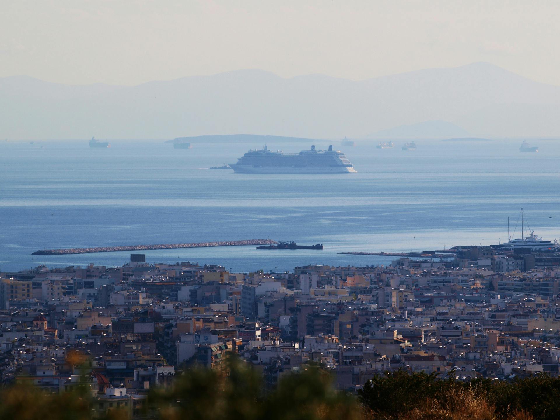 Panoramic view of Athens coastline with cruise ships in the Mediterranean Sea, highlighting urban and maritime scenery.