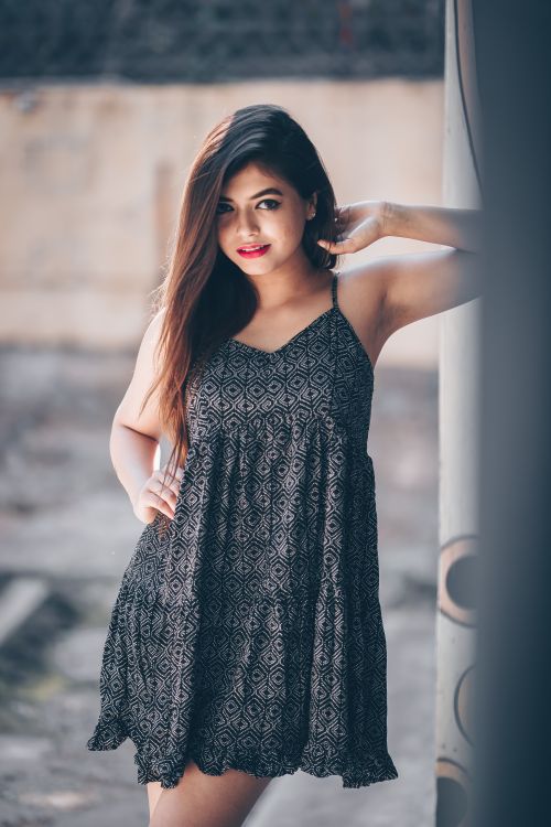 Free Young woman posing confidently in a patterned dress outdoors with a blurred background. Stock Photo