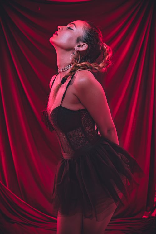 Free Fashion portrait of a woman in a black lace dress against a dramatic red backdrop. Stock Photo