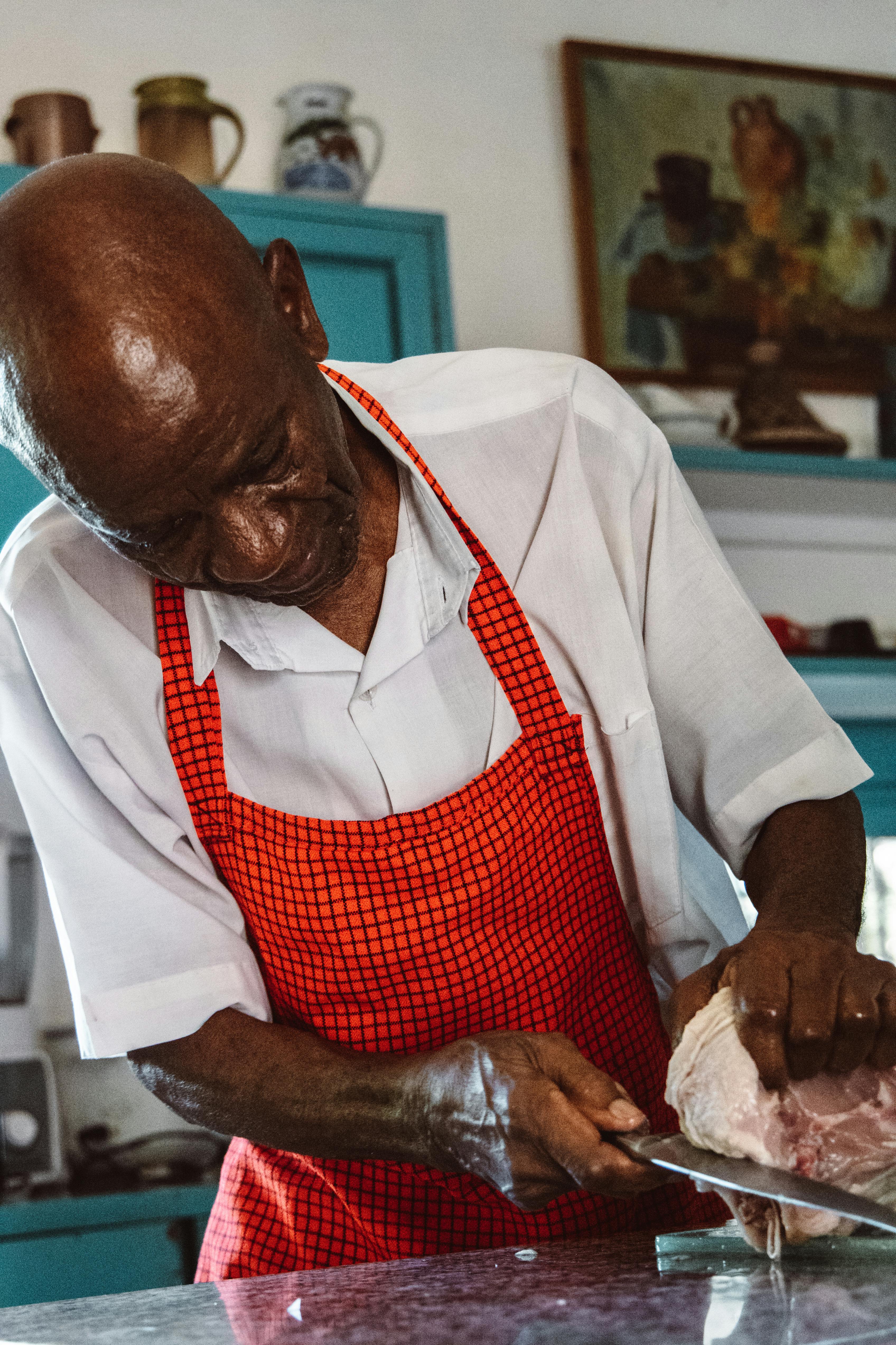 A chef skillfully slices meat on a countertop in a vintage kitchen setting.