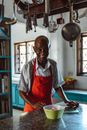 Man in Gray Button Up Shirt and Red Apron Standing Near White Table