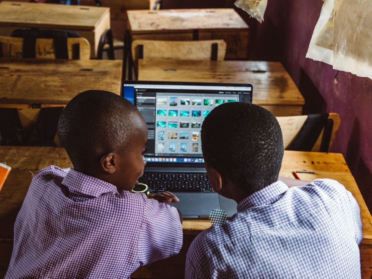 Learners in school uniform using a laptop in class
