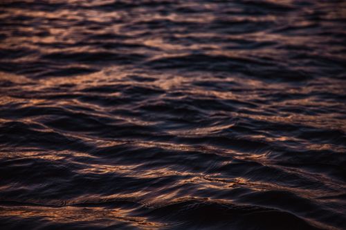 Free Close-up view of tranquil ocean waves with soft sunset reflections, creating a calming atmosphere. Stock Photo