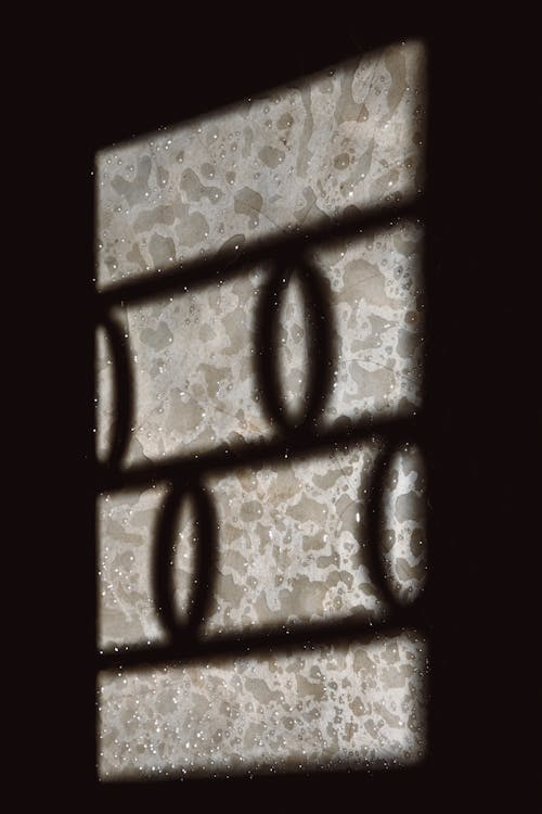 Metal Bars Shadow Cast on a Weathered Glass Surface