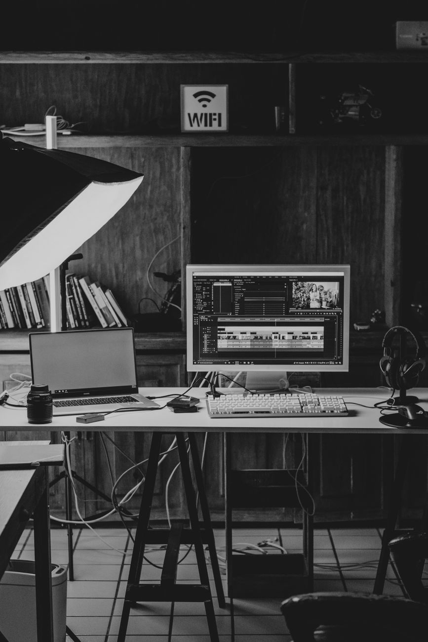 Stylish black and white home office workspace with computers and equipment for video editing.