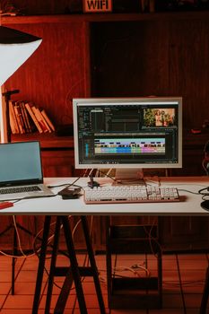 A well-lit desk setup featuring a desktop for video editing and a laptop, ideal for a modern workspace.
