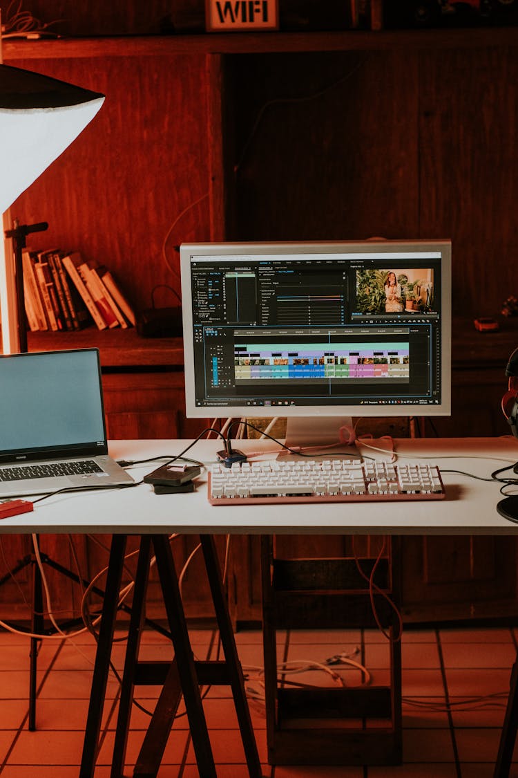 A Laptop Near The Computer Set On The Table