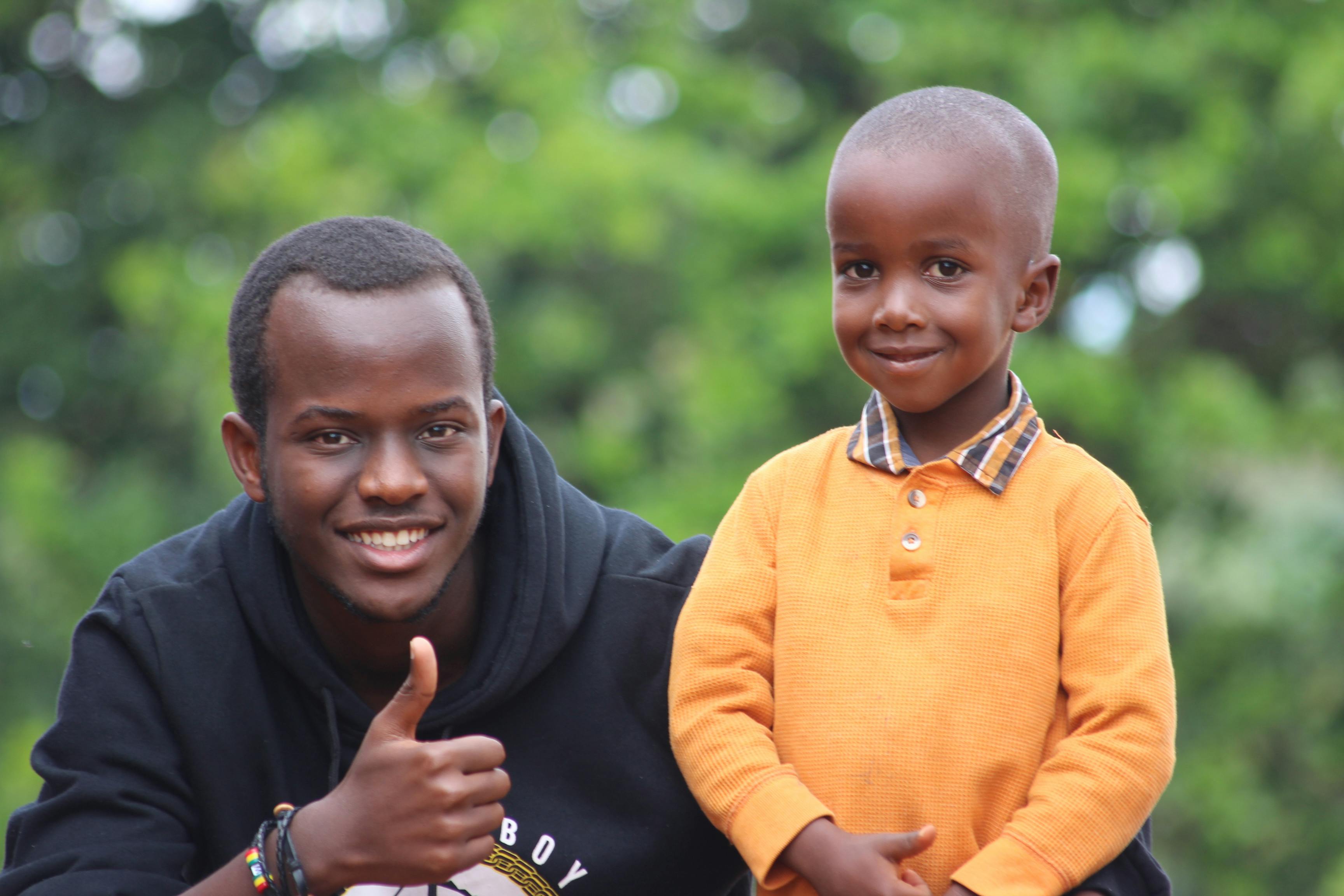 man wearing black hoodie beside boy wearing orange long sleeved polo shirt