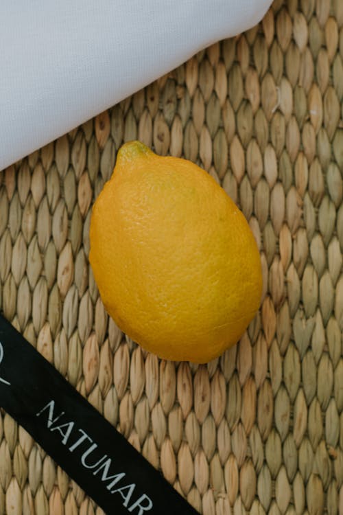 Free A Yellow Lemon on a Woven Mat Stock Photo
