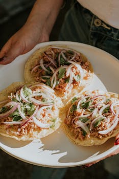 Close-up of three homemade tacos on a plate with fresh toppings, perfect for food enthusiasts.
