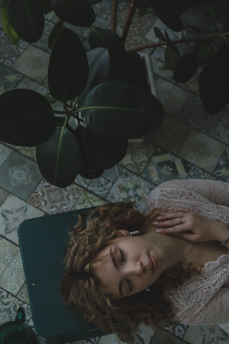 Woman Lying On Chair Surrounded By Plants