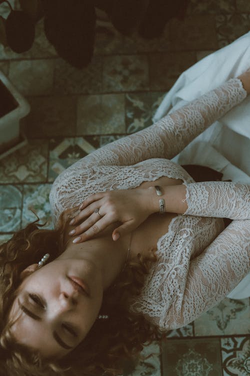 A Woman in White Lace Long Sleeve Shirt Sitting on the Floor