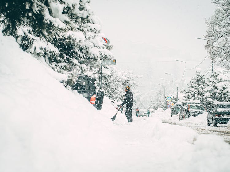 Man Shoveling Snow On Street