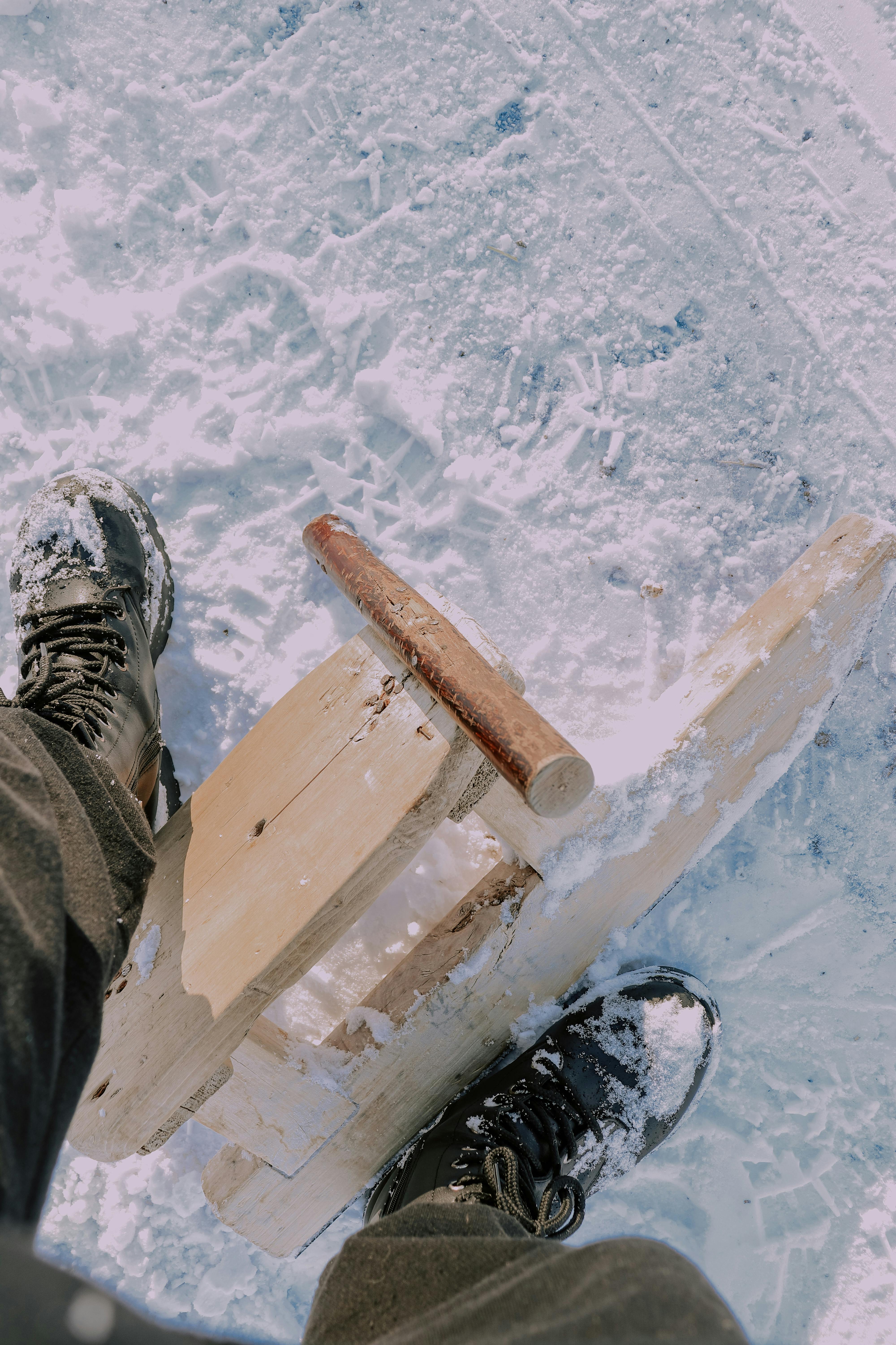 Prescription Goggle Inserts - View of person wearing snow boots standing on a wooden sled in a snowy landscape, captured from above.