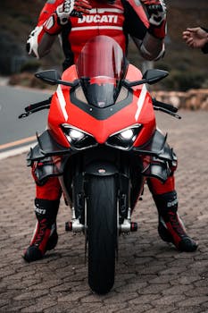 Dynamic close-up of a motorbike racer in a red suit sitting on a Ducati sports bike.