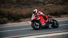 Man in Red and White Motorcycle Suit Riding on Red and White Sports Bike on Road